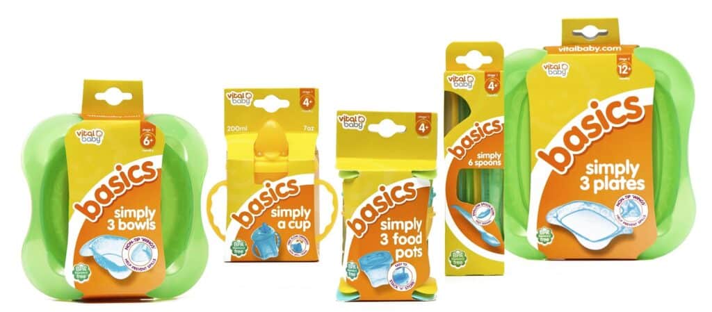 Five Vital Basics "Basics" products: 3 bowls, a cup, 3 food pots, 6 spoons, and 3 plates. Packaging is mostly orange and green with white text—Simply Everything You Need for your baby’s mealtimes, with each item shown or illustrated on the pack.