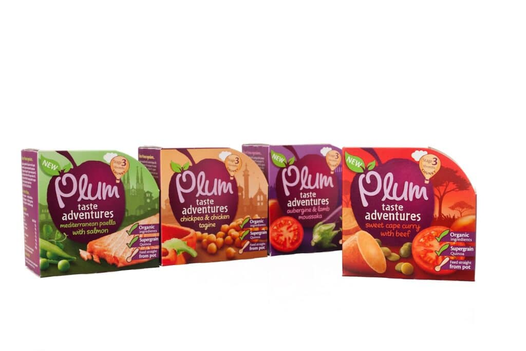 Four Plum Taste Adventures food boxes are displayed in a row on a white background, each featuring vibrant colours and images of the meal inside, such as paella, tagine, aubergine stew, and sweet cape curry—inviting you to savour a world of taste.