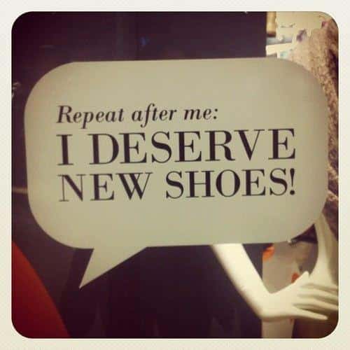 A speech bubble sign reads: "Repeat after me: I DESERVE NEW SHOES!" with part of a mannequin visible in the background.