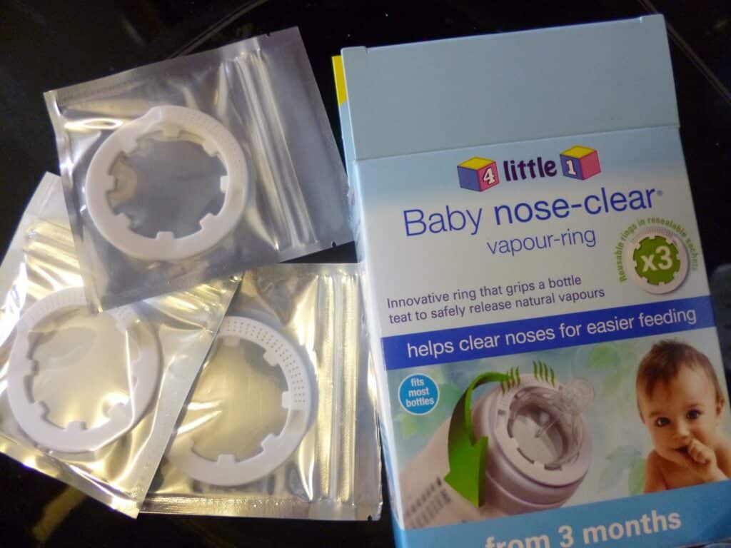 A box labelled "Baby Nose Clear Vapour Ring" sits beside three individually packaged white plastic vapour rings. The box shows a baby and claims to offer Baby Nasal Relief for easier feeding from three months old.
