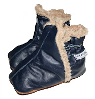 A pair of dark blue leather SKEANIE Shoes baby bootees with light brown fleece lining and soft soles, positioned side by side on a white background.
