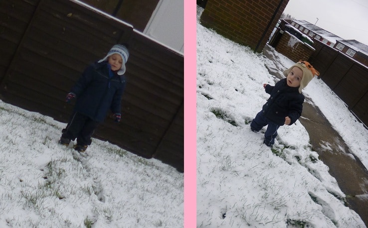 Two young children dressed in winter coats and hats stand outside on a patchy snow-covered garden, separated by a vertical pink border. A house and fenced garden are visible in the background, capturing a perfect Let It Snow moment.