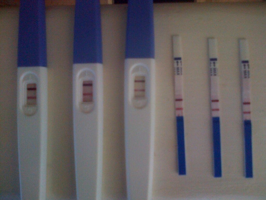 Four pregnancy tests: three stick tests with two visible lines each and three strip tests, also showing two lines each, all indicating positive results, on a white surface—perhaps another reason to consider a house extension.