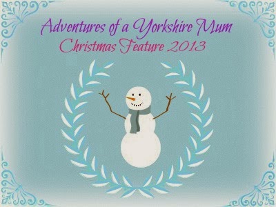 A festive graphic with a smiling snowman in a laurel wreath on a blue background. Text reads "Adventures of a Yorkshire Mum Christmas Feature 2013" in purple and pink script, inspired by the magic of Leeds Christkindelmarkt. Decorative blue corners frame the image.