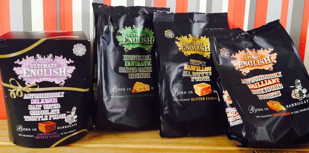 Four packages of Ultimate English confectionery stand side by side. The black packaging features different coloured text for each flavour, including chocolate truffle fudge, salted caramel fudge, and butter fudge—classic British sweets.