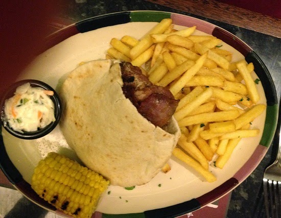 A plate with a pitta sandwich containing meat, served with chips, corn on the cob, and coleslaw—just one of the tempting options you might find on Frankie & Benny's Christmas Menu.