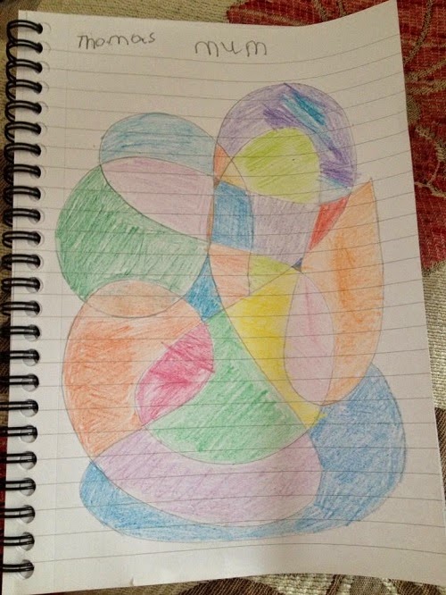 A notebook page shows a colourful abstract drawing with overlapping shapes, each filled with different colours. "Thomas" and "Mum" are written at the top of the lined paper, capturing a special moment for this Week In Pictures.