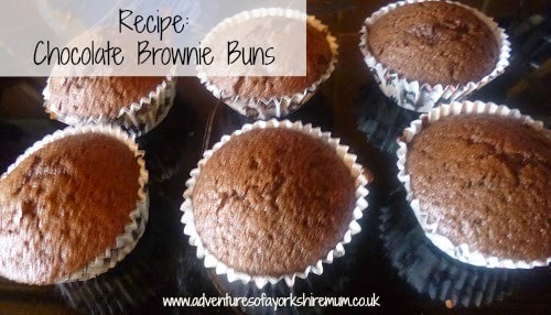 Six chocolate brownie buns in paper cases arranged on a dark surface, with "Recipe: Chocolate Brownie Buns" written on the image and a website URL below. Perfect for anyone craving irresistible chocolate brownie buns at home.