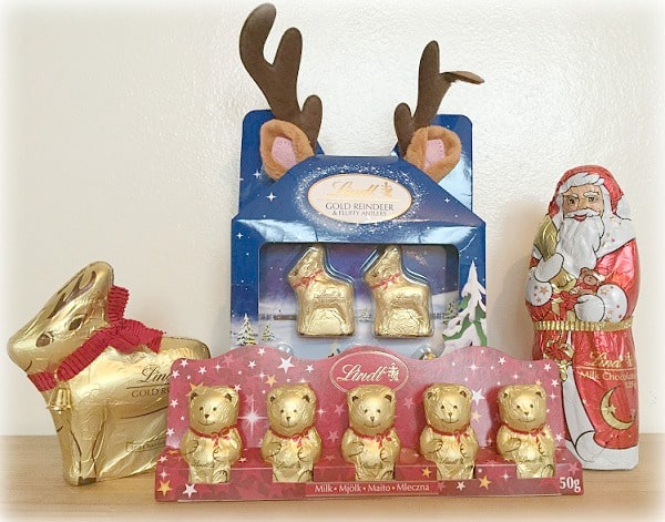 A display of festive Lindt chocolate figures—including a gold reindeer, gold bears, Father Christmas, and two reindeer-shaped chocolates in a blue package with brown felt antlers—perfect for the Christmas Gift Guide or as Christmas presents.