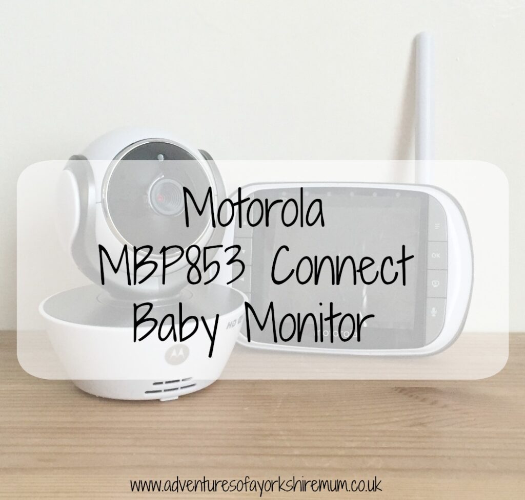 A Motorola baby monitor MBP853 Connect with camera and screen units sits on a light wood surface. The text "Motorola MBP853 Connect Baby Monitor" is overlaid in large font.