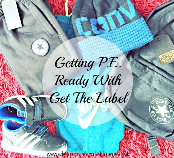 Flat lay of kids' sportswear and accessories on a red carpet, including a Converse beanie, rucksack, black shorts, blue Adidas trainers, and a blue Nike T-shirt—everything you need to get P.E. ready with Get The Label.
