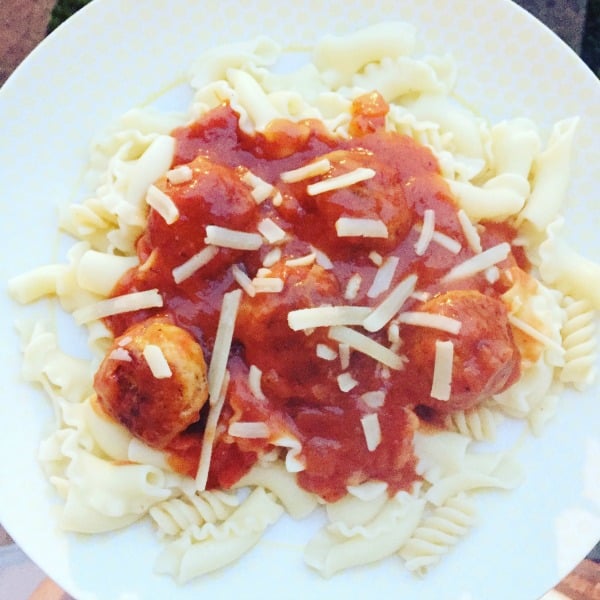 A plate of pasta topped with tomato sauce, meatballs, and grated cheese from the Full Heck Deck, served on a white plate with a light pattern.