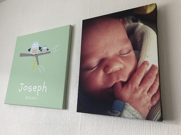 A canvas print of a sleeping newborn baby lies next to a green canvas with two cartoon birds, the name "Joseph," and the date "08.02.2015," both making it easy to display photos of your favourite moments around the house.