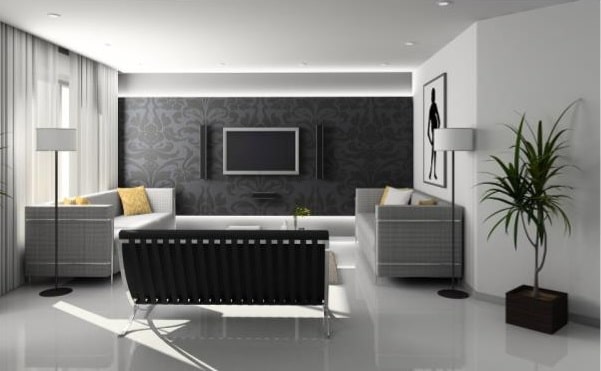 Modern living room with white flooring, two grey sofas, a black bench, and a wall-mounted TV on a dark feature wall. Floor lamps, a potted plant, and wall art decorate the space. Light from large windows brightens the room.