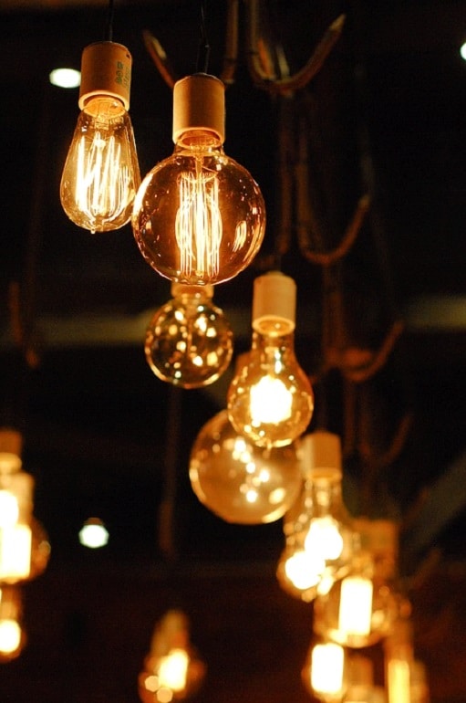 A group of vintage-style incandescent light bulbs hanging from cords, glowing warmly against a dark background, brings a touch of garden design inspiration to any space, creating a cosy and inviting atmosphere.