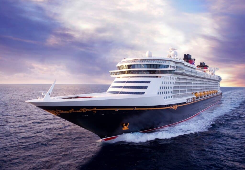 A large cruise ship sails through calm ocean waters at sunset, its bow angled toward the viewer. Sunlight reflects on the waves, creating an inviting scene perfect for a memorable family cruise or holiday escape.