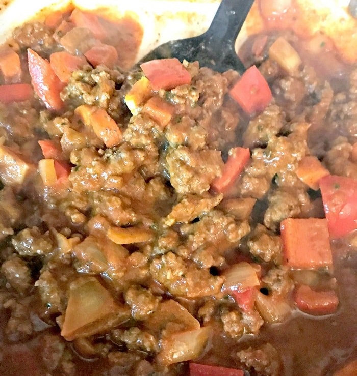 Close-up of a hearty meat and vegetable stew from the WW Smart Kitchen, featuring browned minced beef, chopped red peppers, and onions in a rich sauce. A black spatula is partially visible stirring this delightful healthy meal.