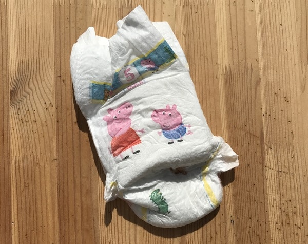 A disposable nappy for toddler potty training, featuring cartoon characters Peppa Pig and George Pig, lying on a wooden surface.