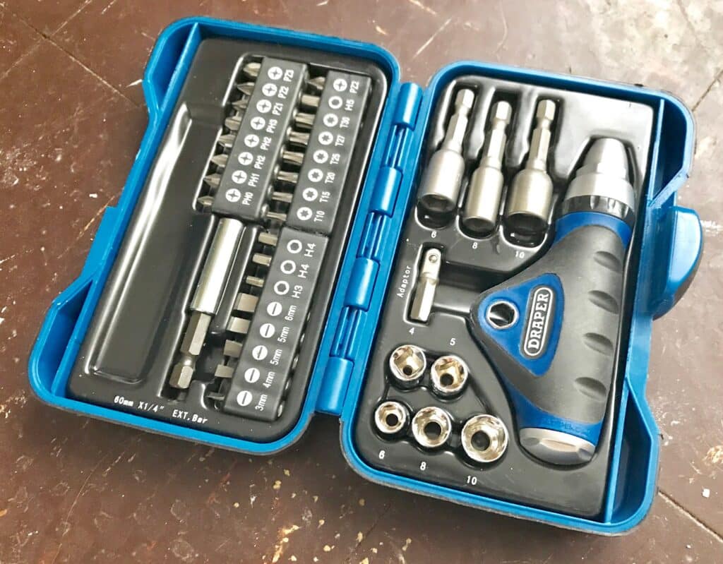 A blue plastic case containing a multi-bit screwdriver set, perfect for buying tools to meet your DIY needs. Includes a handle, various bits, sockets, extensions, and adaptors, all neatly organised in individual compartments.
