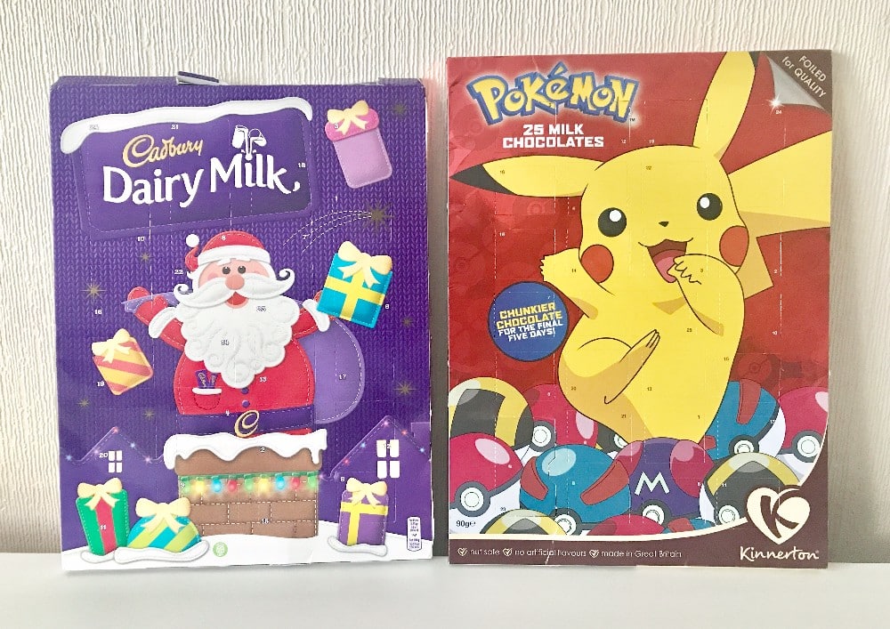 Two Christmas Advent Calendars side by side: one Cadbury Dairy Milk with a cartoon Father Christmas holding presents, and one Pokémon calendar featuring Pikachu surrounded by Poké Balls—perfect for family festive fun.