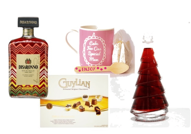 A bottle of Disaronno, a pink "Cake For One Special Mum" mug, a wooden spoon, a slice of cake, Guylian chocolates, and a festive Christmas tree-shaped glass bottle—a perfect addition to any Christmas Gift Guide for Women.