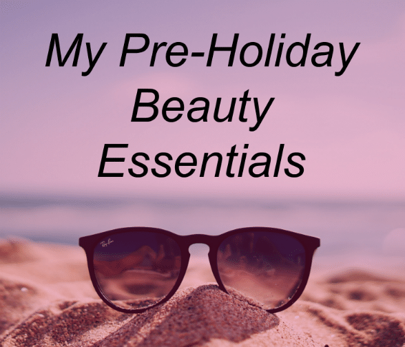 A pair of Ray-Ban sunglasses rests on sandy beach with a pink-purple sky. Overlaid text reads: "My pre-holiday beauty essentials.