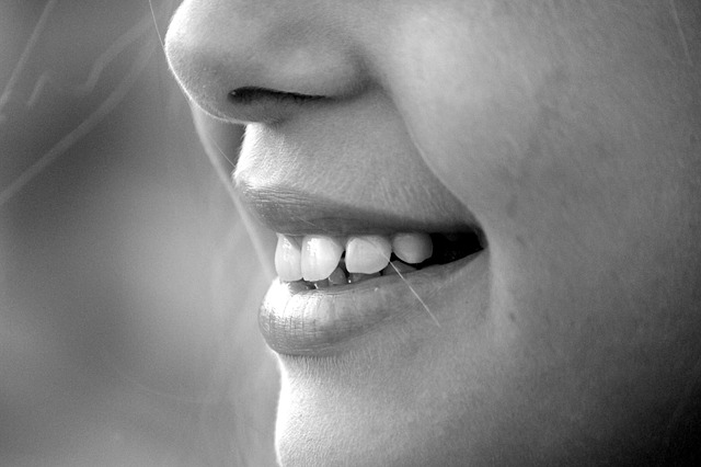 A close-up, black-and-white photo of a person's face focuses on their mouth and nose. The person is smiling, showing healthy teeth and lips clearly. The image asks, What Should You Eat For A Healthy Smile?, and conveys a sense of happiness.