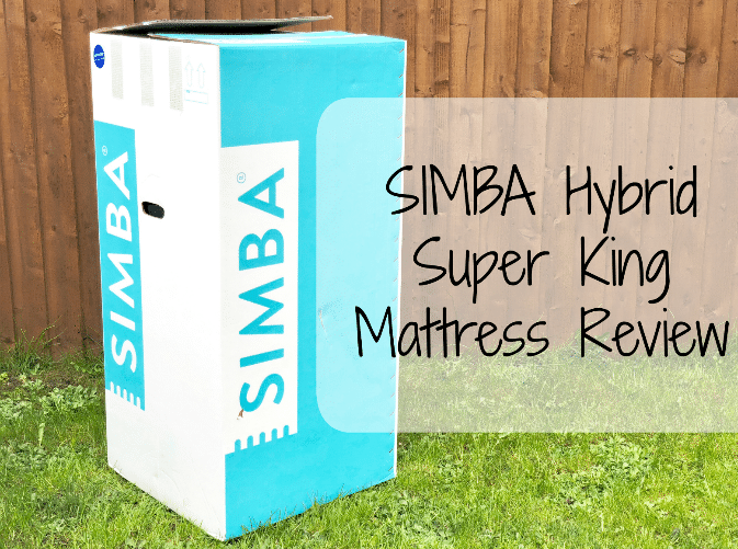 A large box labelled "SIMBA" stands on the grass in front of a wooden fence. Text overlay reads: "Simba Hybrid Super King Mattress Review – Our honest mattress review.
