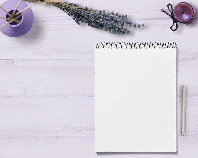 A blank spiral notebook with a pen lies on a light wooden surface. Nearby are dried lavender, a purple ribbon, and twine, creating an elegant workspace—perfect for jotting down CV tips to help make your CV stand out.