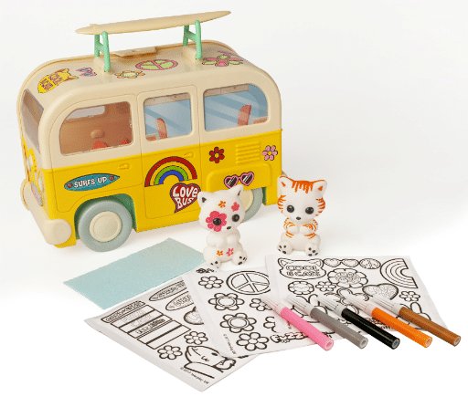 A toy yellow Campervan Carry Case with surfboards, two small Fuzzikins cat figurines, colouring sheets with peace and flower designs, and several coloured markers are arranged together on a white surface. Win this fun creative set!.