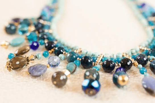A close-up of a beaded necklace featuring clusters of blue, turquoise, and gold beads in various shapes—an elegant accessory that makes thoughtful Birthday Gift Ideas for Mum.