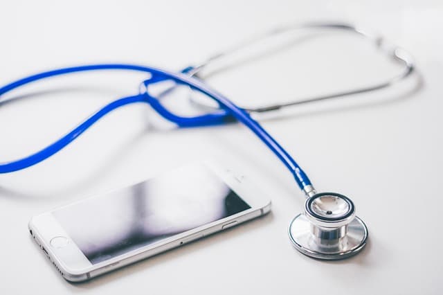 A blue stethoscope and a smartphone lying on a white surface, symbolising how to spot health conditions using technology and recognising important signs.