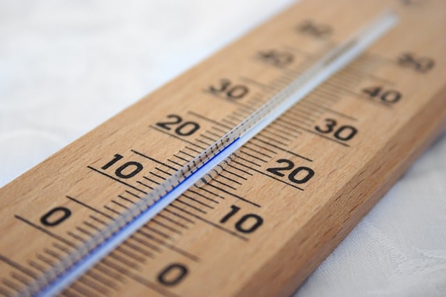 Close-up of a wooden thermometer at home, its mercury level showing the correct temperature around 20°C (68°F) in both Celsius and Fahrenheit.
