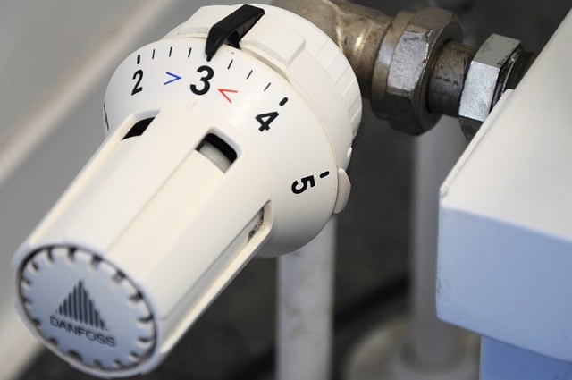 A close-up of a white Danfoss radiator thermostatic valve, numbered 1 to 5, helps you set the right temperature for optimal home comfort. The valve is attached to a metal pipe with a clear arrow indicator.
