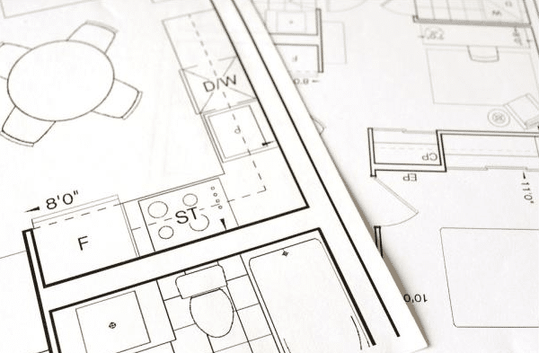 Close-up of architectural floor plans for homes, showing the layouts of rooms, pre-installed kitchen appliances, a bath, and a toilet, along with scaled measurements and technical drawing details.