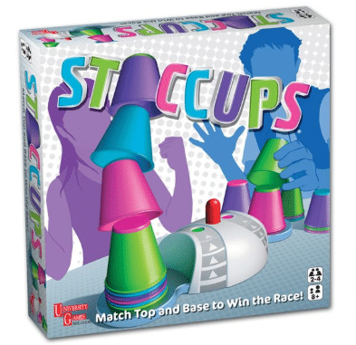 The image shows the box for the board game "Staccups" by University Games, featuring stacked colourful cups and two illustrated people racing to win. The tagline reads, āMatch Top and Base to Win the Race!ā.