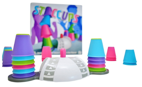 Colourful plastic cups stacked in towers beside a white and grey game buzzer, with the "Staccups" game box from University Games visible in the backgroundāperfect for a fast-paced challenge where players race to win!.