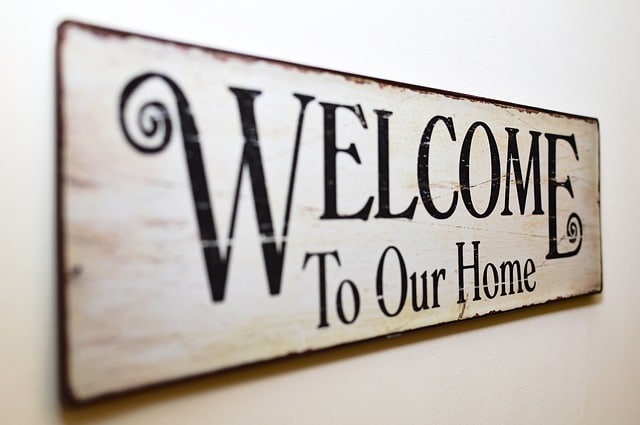 A rustic wooden sign with black, decorative text reads "WELCOME To Our Home" and hangs on a white wall, offering warmth and inspiration for Ways To Make Your Home Elderly-Friendly.