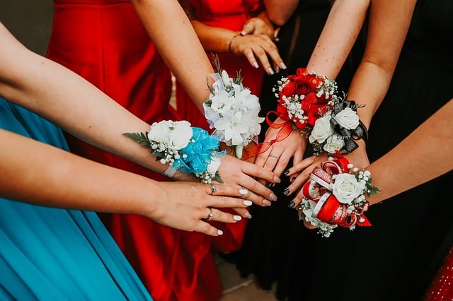 A group of people in formal dresses stand in a circle, extending their hands together to display colourful corsages with flowers and ribbons—a classic scene at American Style Proms.