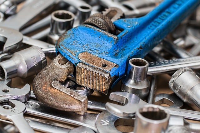 A worn blue pipe spanner rests on a pile of silver spanners and sockets, showcasing hand tools commonly used for mechanical or plumbing work—perfect for tackling easy boiler maintenance or picking up new boiler tips.
