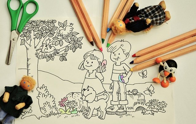 A colouring page with two children and a dog outdoors, surrounded by coloured pencils, toy figures, and a green-handled pair of scissors. Some parts of the drawing are partially coloured, showing the fun of animals in education at home.
