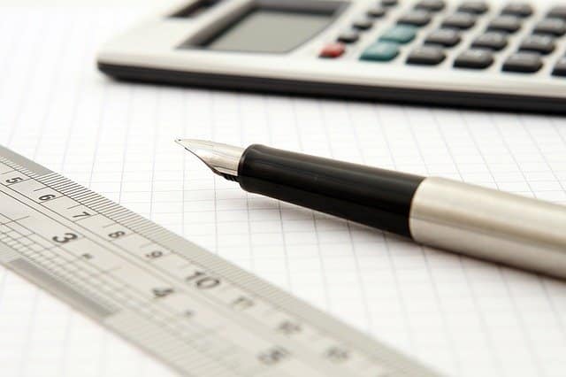 A fountain pen, metal ruler, and calculator rest on a sheet of graph paper, suggesting a workspace for kids' maths or anyone seeking help with maths and technical drawing.