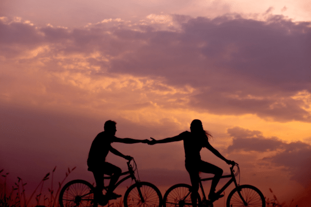 A silhouette of a two people on bicycle