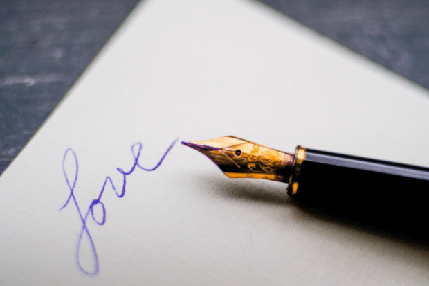 A fountain pen and paper with love written on it