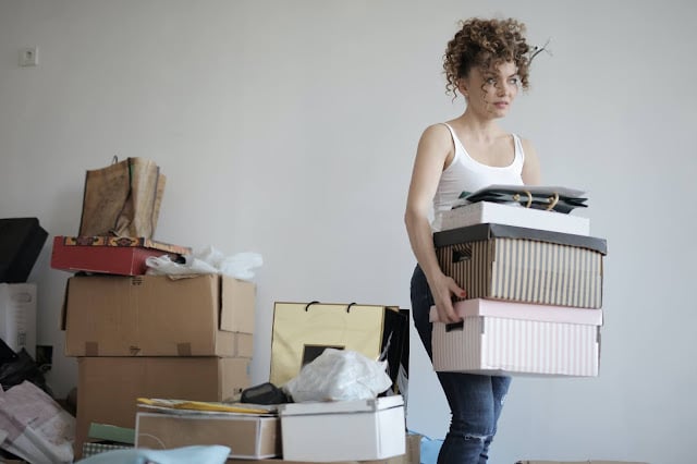 A woman moving lots of boxes and clutter