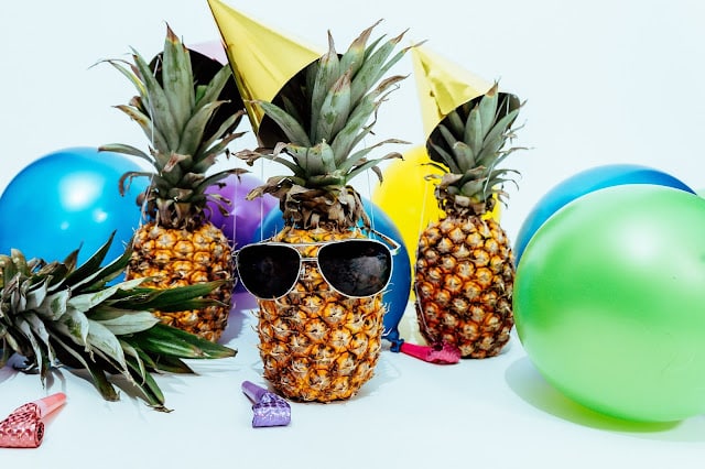 Summer Party decorations including streamers, balloons and pineapples with sunglasses on