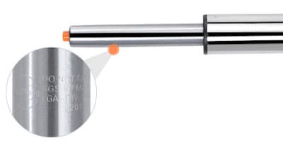Close-up of a metal cylinder with an orange tip, similar to those found on height-adjustable bar stools. A magnified inset shows engraved text on the cylinder’s surface, though the text appears blurry and unreadable.