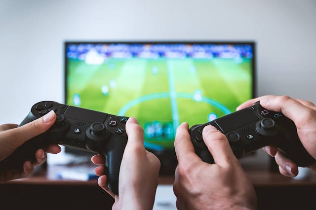 Two people playing a football video game on a PS4