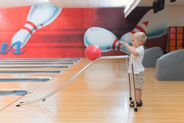 A small boy using a bowling aid in a bowling alley