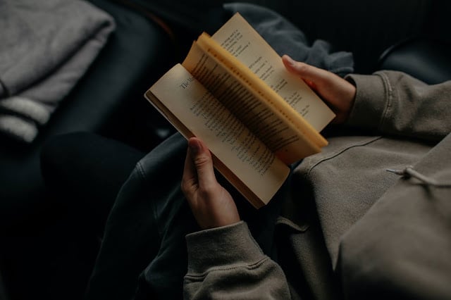 A person reading a book sat on a sofa